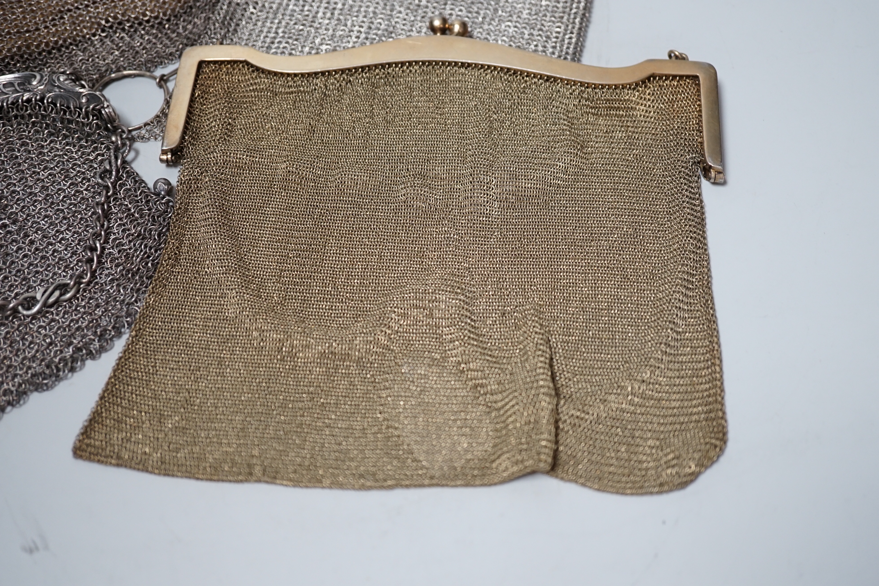 A George V silver gilt mesh evening bag, retailed by Mappin & Webb, Birmingham, 1916 and a smaller silver evening bag, a Chinese white metal mesh evening bag, maker LH and a German 900 standard white metal mesh evening b